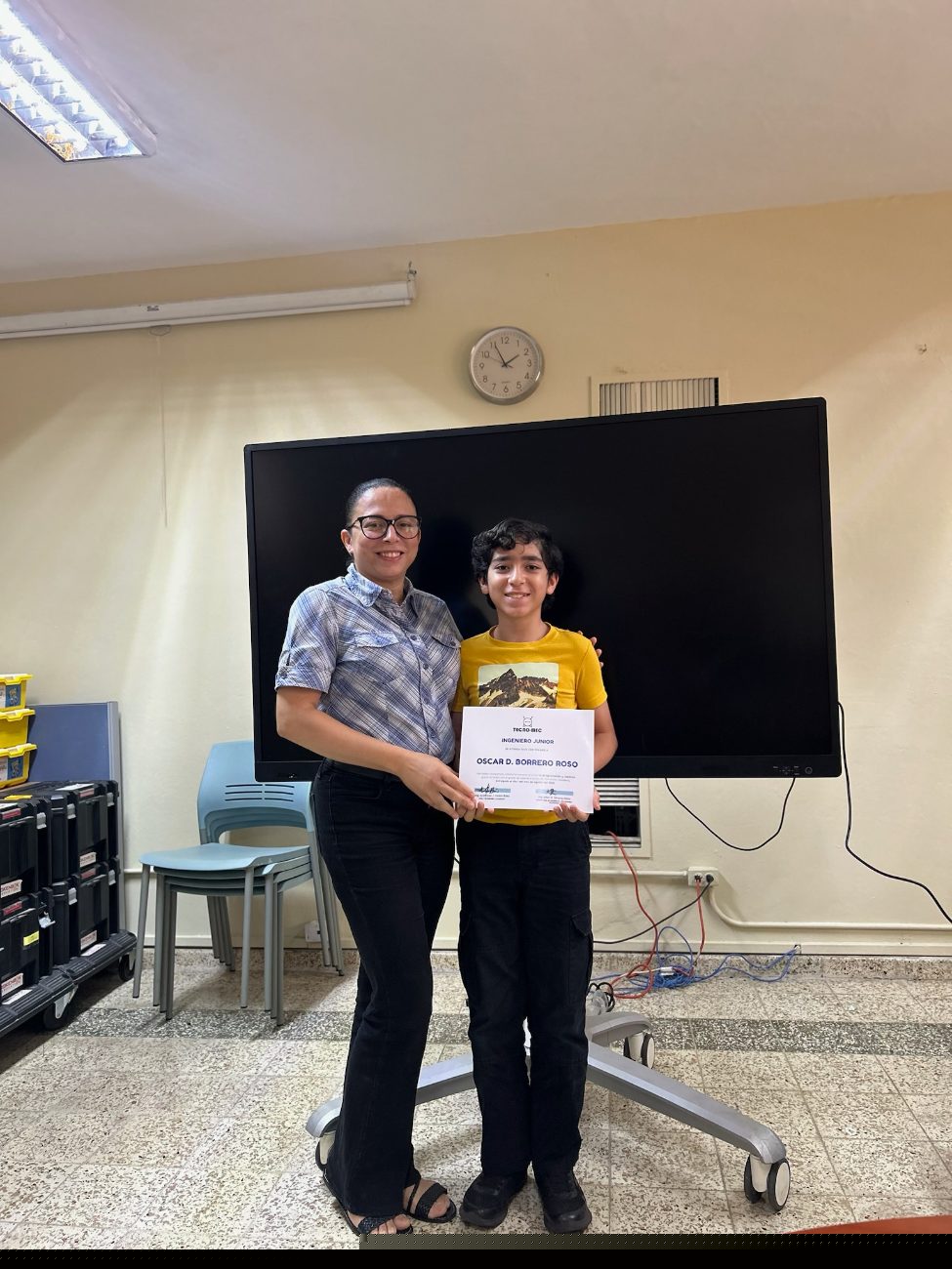 Un estudiante junto a su mamá con el certificado de Ingeniero Junior