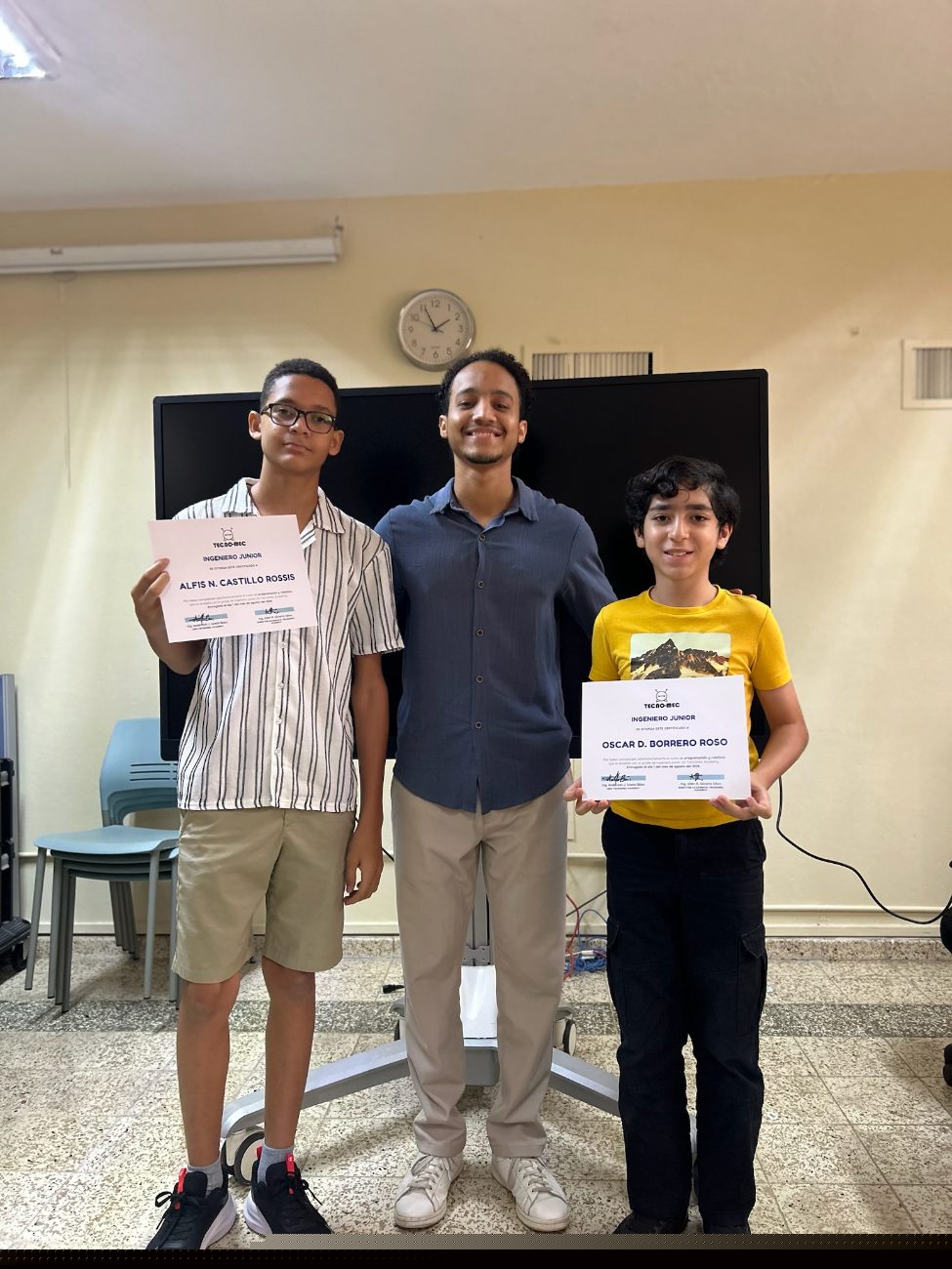 Dos estudiantes muestran su certificado junto a su instructor